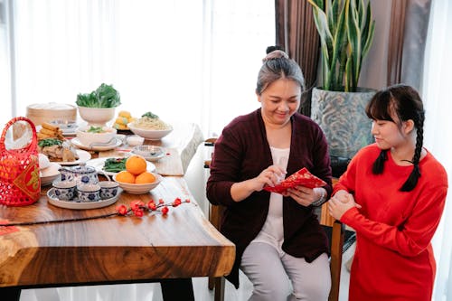 Asian grandma with envelope against granddaughter during New Year holiday