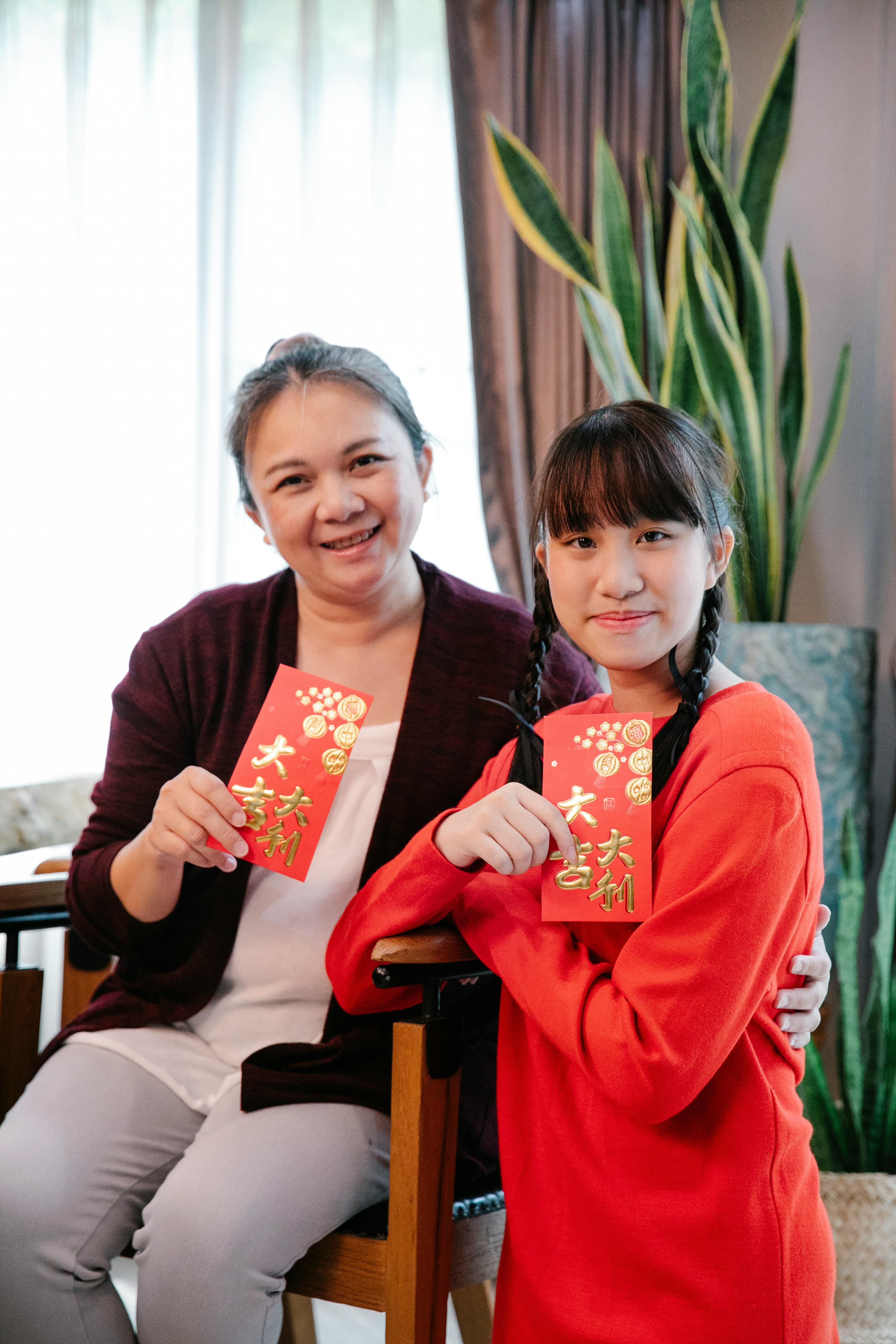 cheerful asian grandmother with granddaughter showing new year envelopes