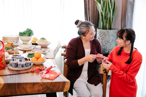 Smiling Asian grandma talking to granddaughter during New Year holiday