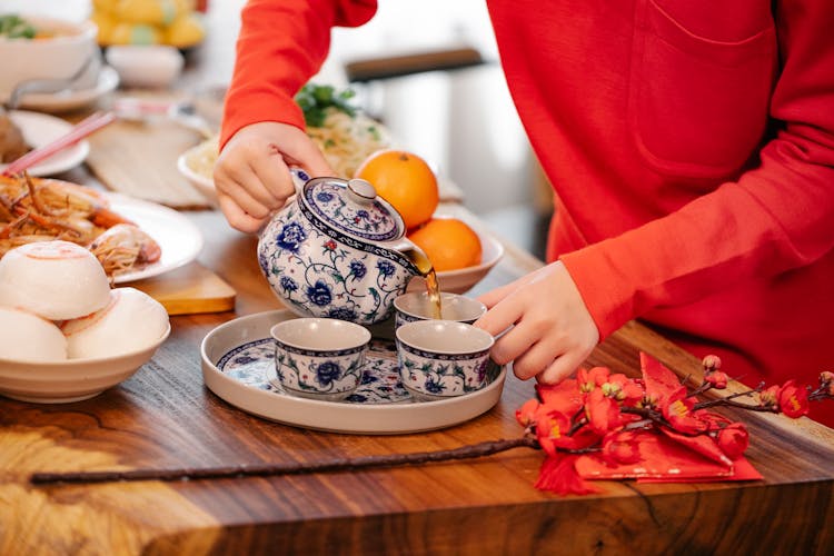 Crop Woman Serving Green Tea At Table With Asian Food