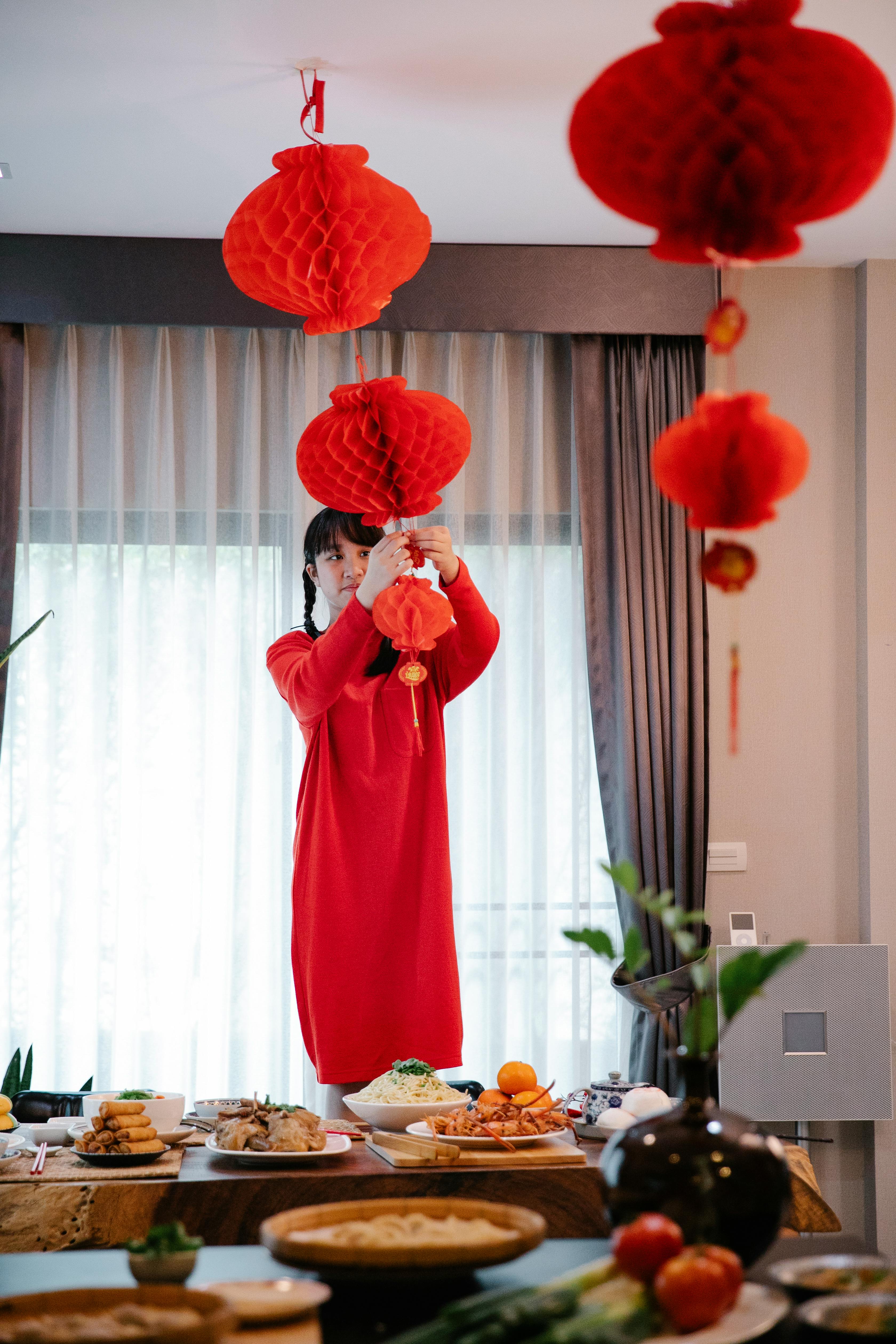 asian teen decorating home with red lanterns during festive occasion