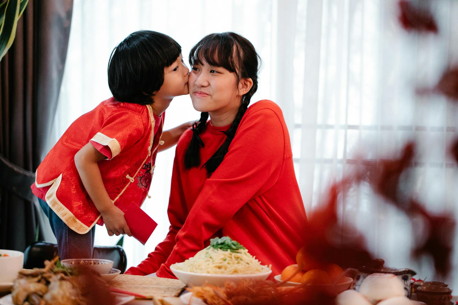 Asian boy kissing sister during New Year holiday at home