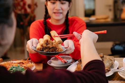 Asian teenager offers a plate of spring rolls during a cozy family meal.