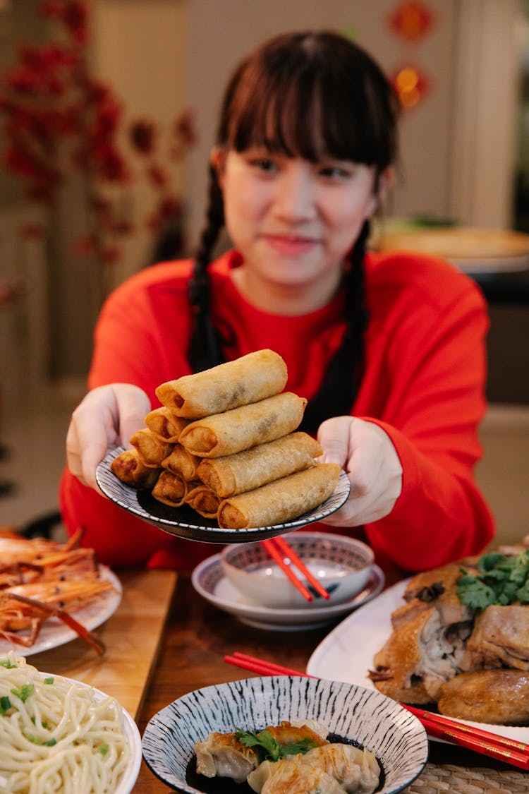 Smiling Asian Teen With Delicious Spring Rolls At Table