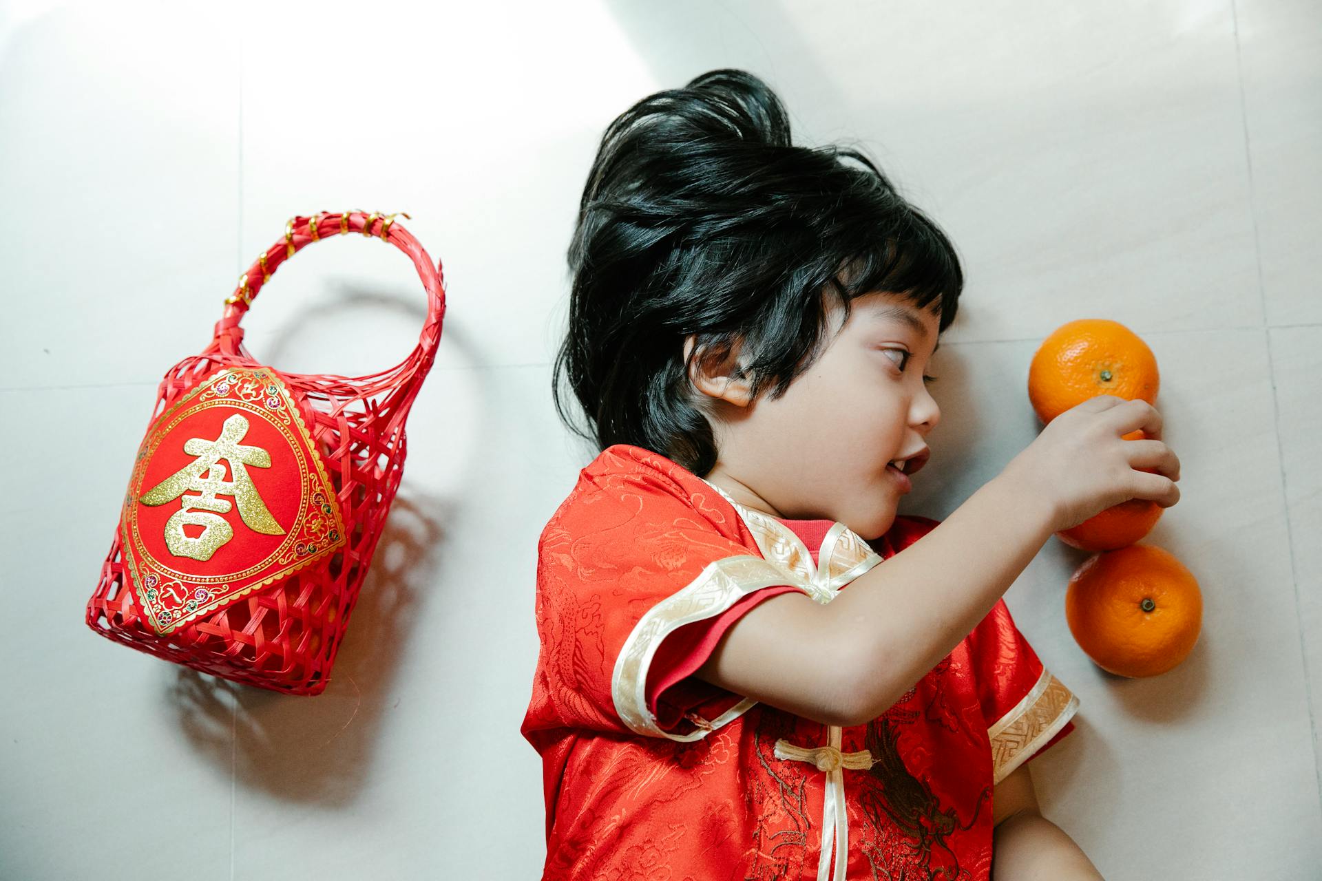 Asian boy on floor with fresh oranges and gift basket