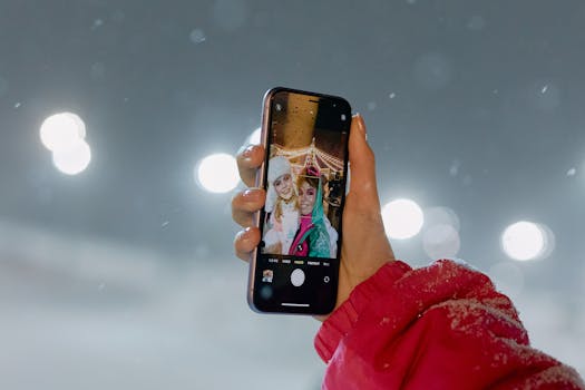 A person taking a selfie with friends outdoors in winter, capturing a joyful moment under night lights.