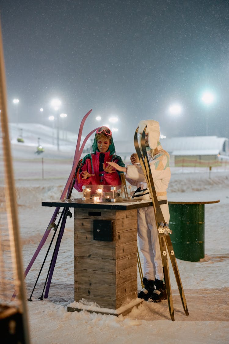 Two People In Winter Clothing Holding Skis