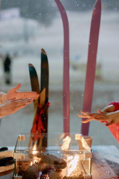 Free Hands warming by a fire with skis in the background on a snowy winter day. Perfect winter retreat scene. Stock Photo