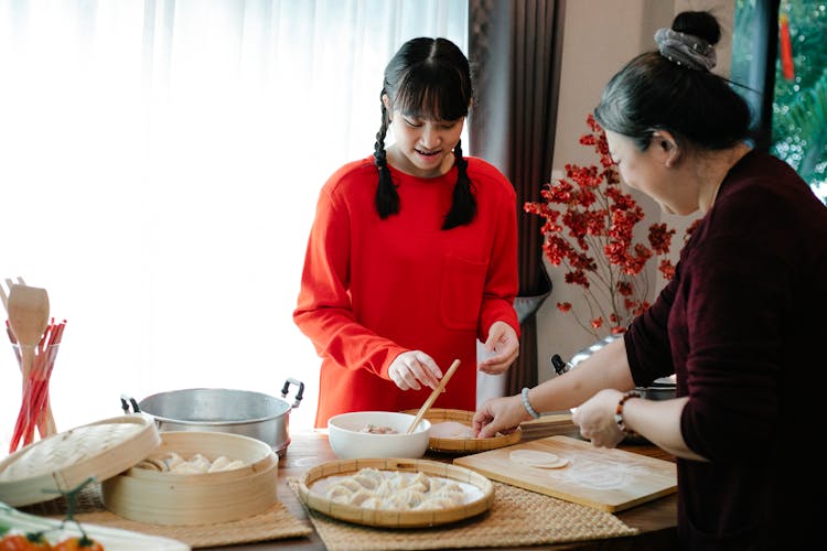 Asian Grandmother With Teenager Cooking Dim Sum At Home