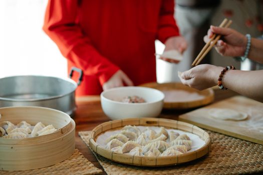 Crop relatives filling dim sum in kitchen