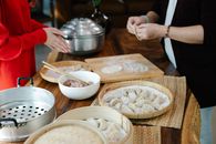 Side view of crop anonymous female relatives cooking dumplings with minced meat filling at kitchen table