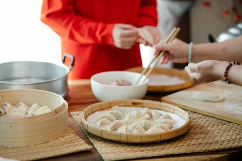 Crop woman with relative filling dim sum in kitchen
