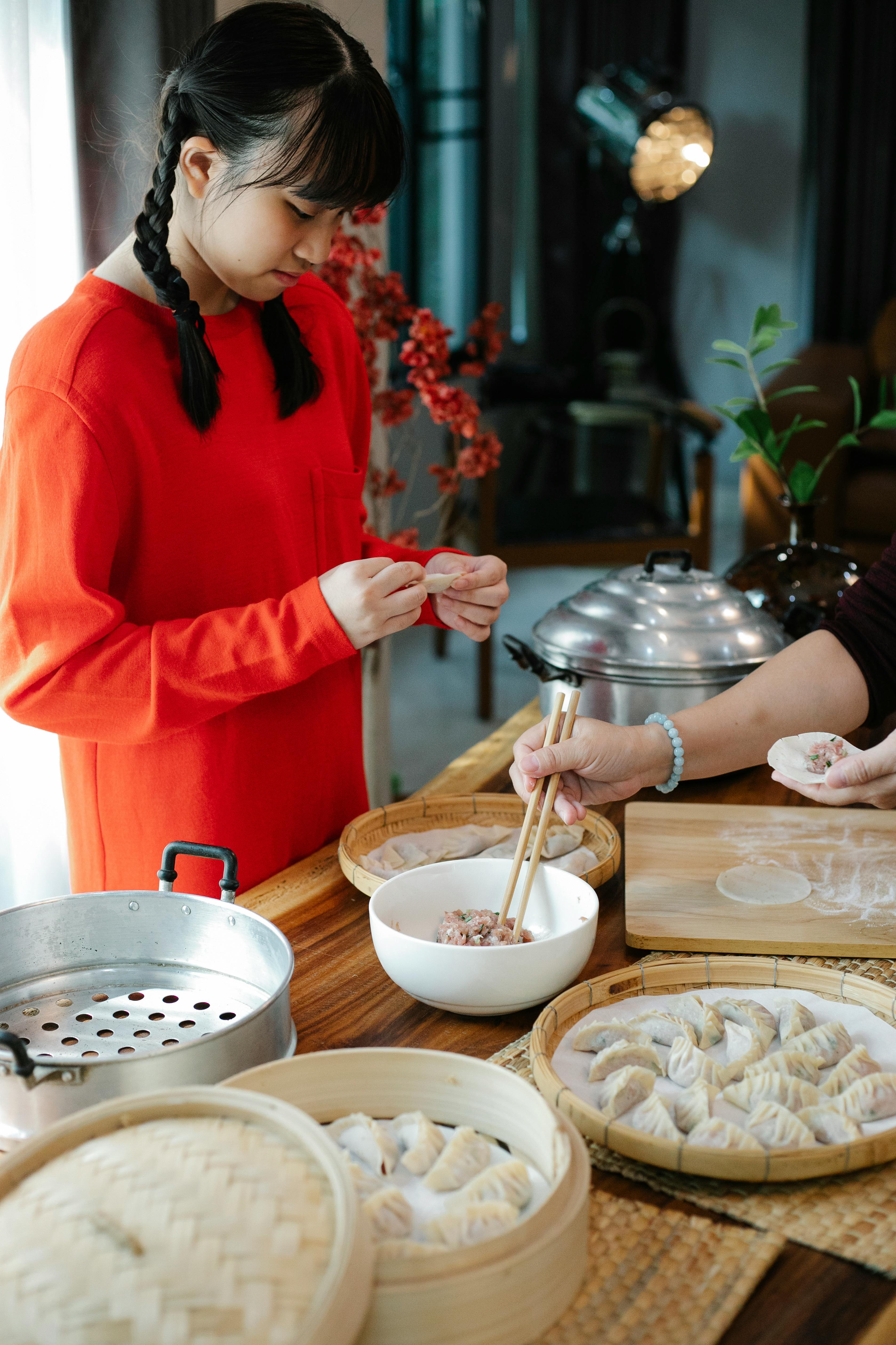 asian teen with crop woman filling dim sum in kitchen