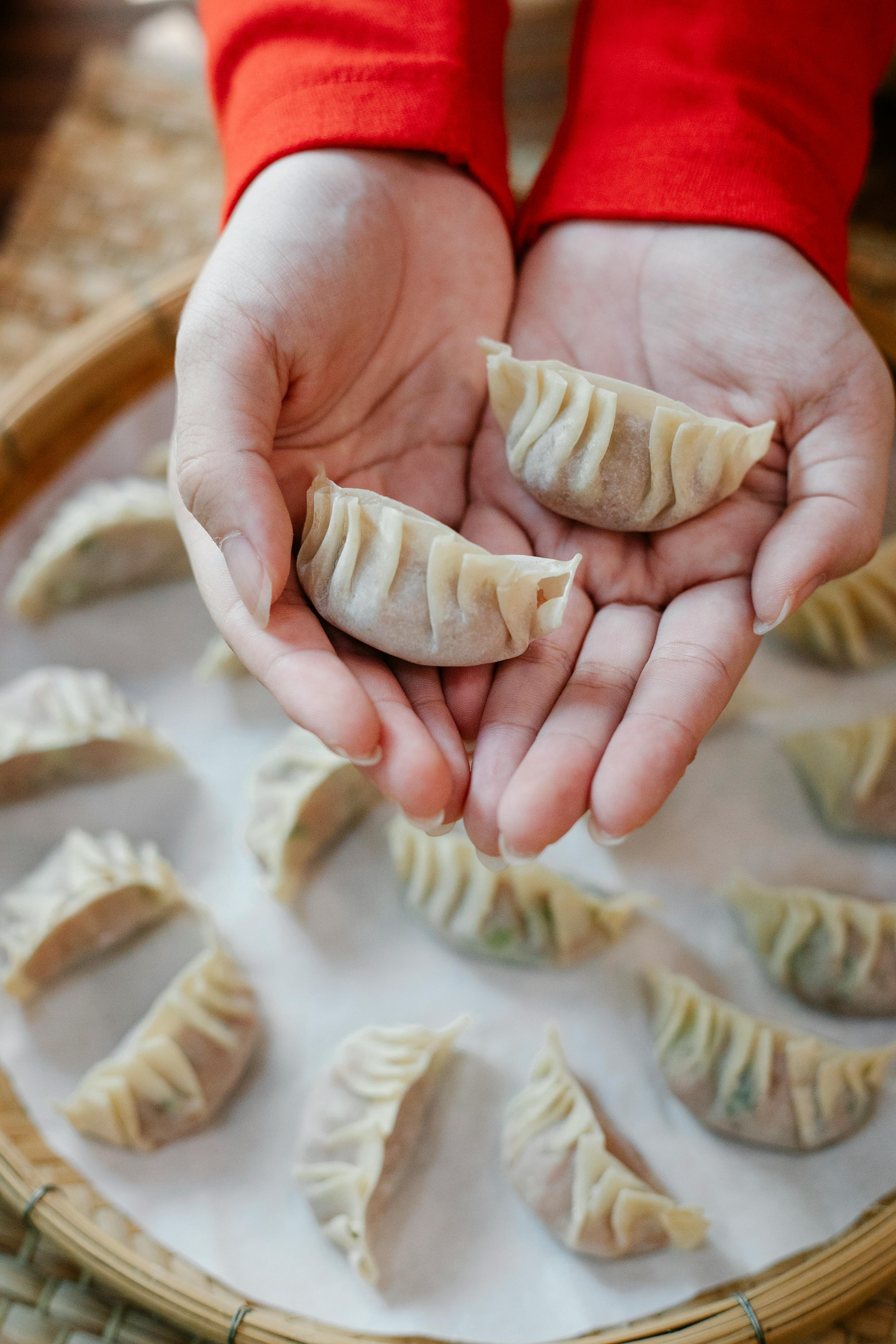 anonymous woman showing chinese dumplings during cooking in kitchen