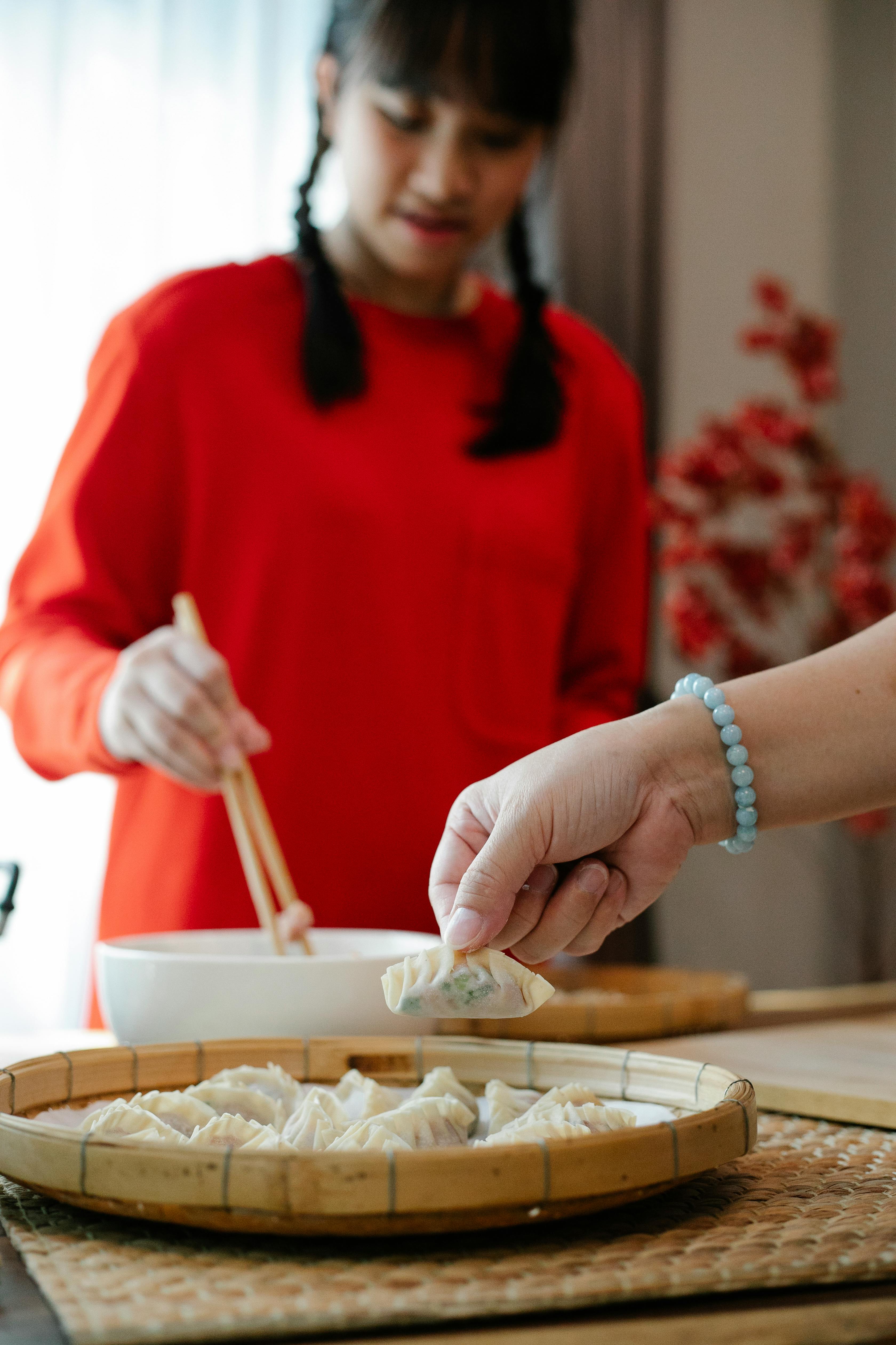 ethnic teen girl cooking in kitchen with anonymous mother