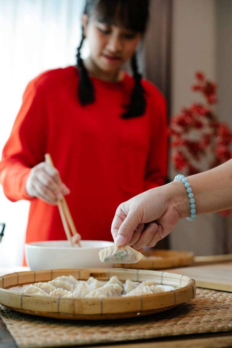 Ethnic Teen Girl Cooking In Kitchen With Anonymous Mother