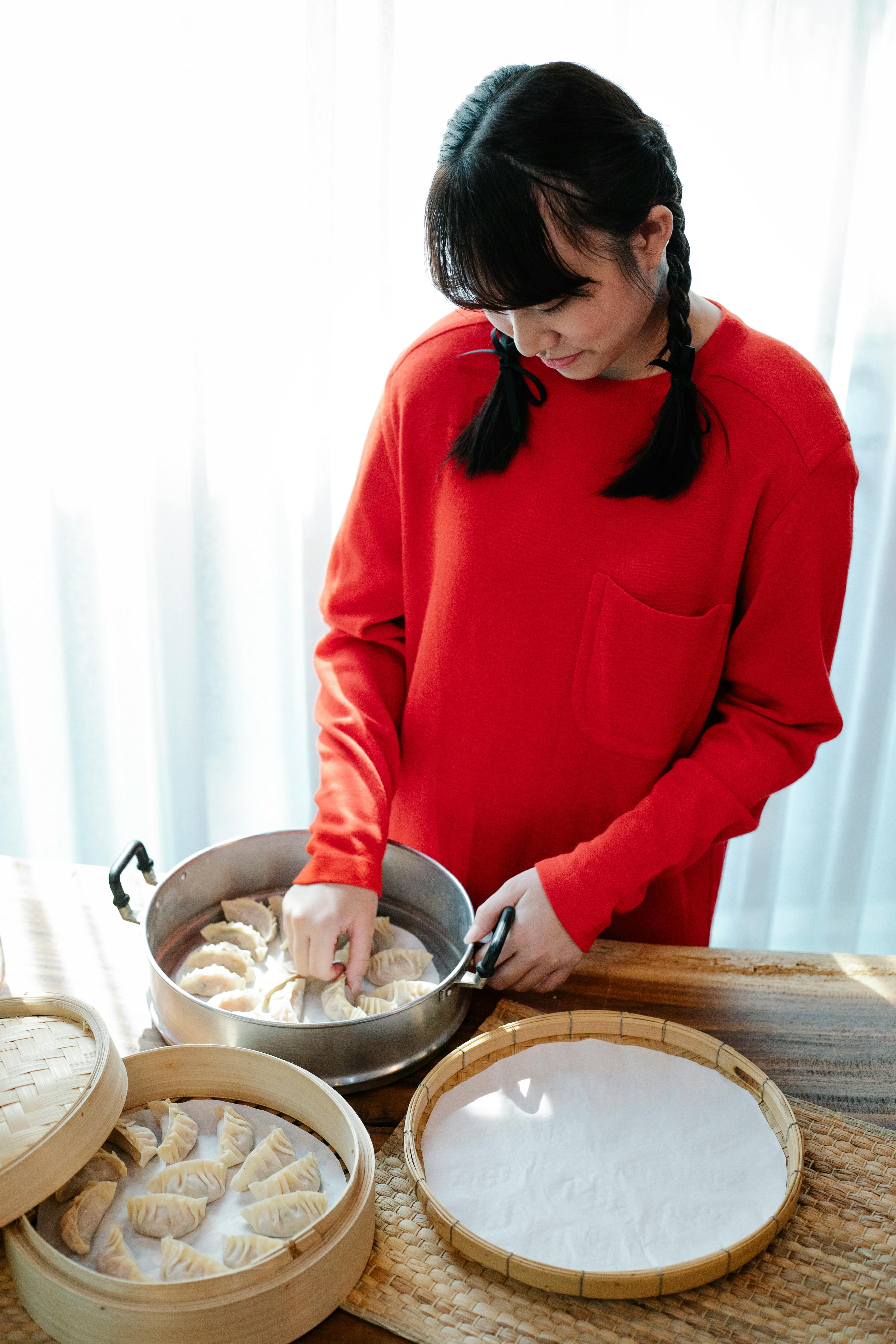 smiling young ethnic preparing traditional jiaozi in kitchen