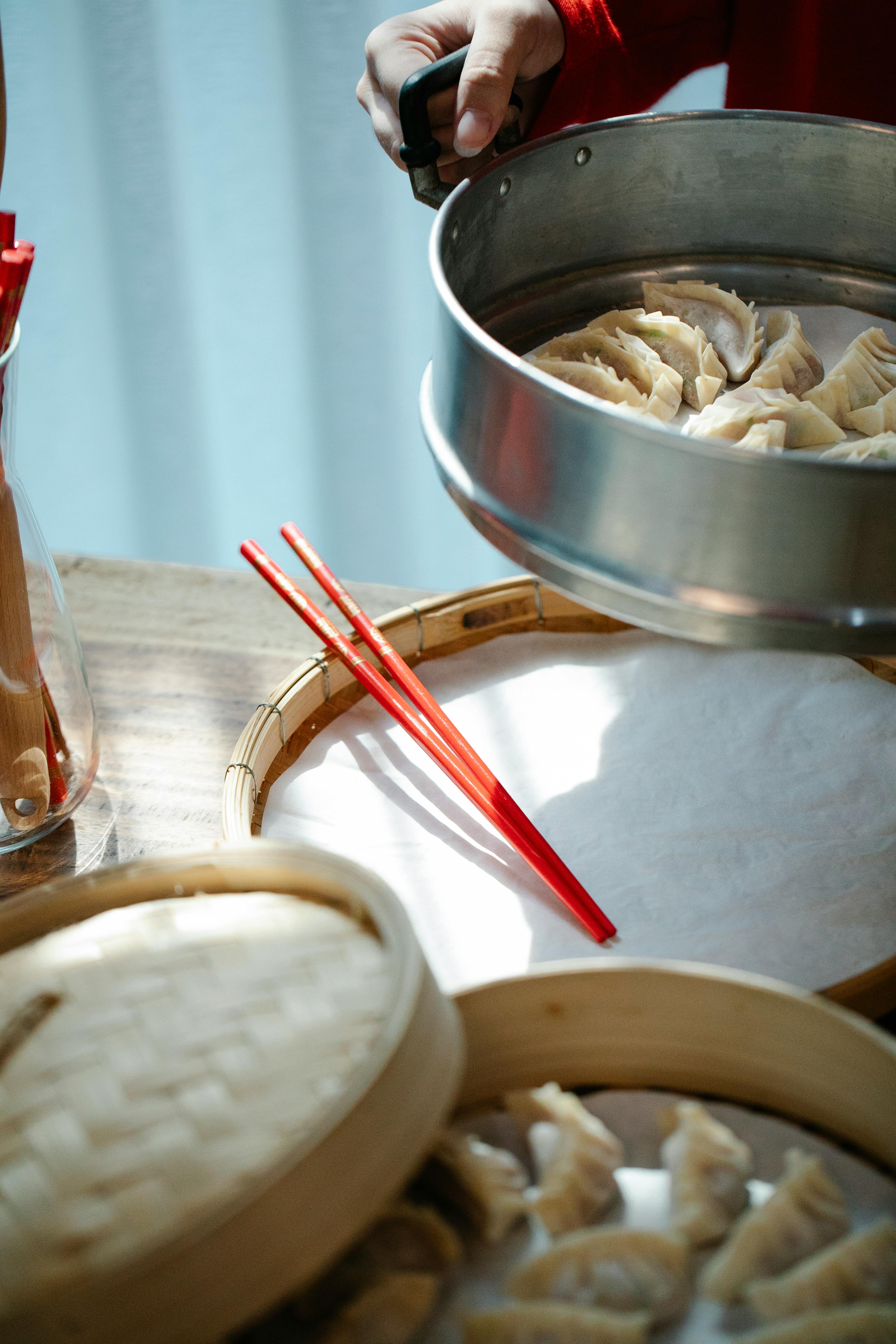 anonymous woman putting pan with raw dumplings on table