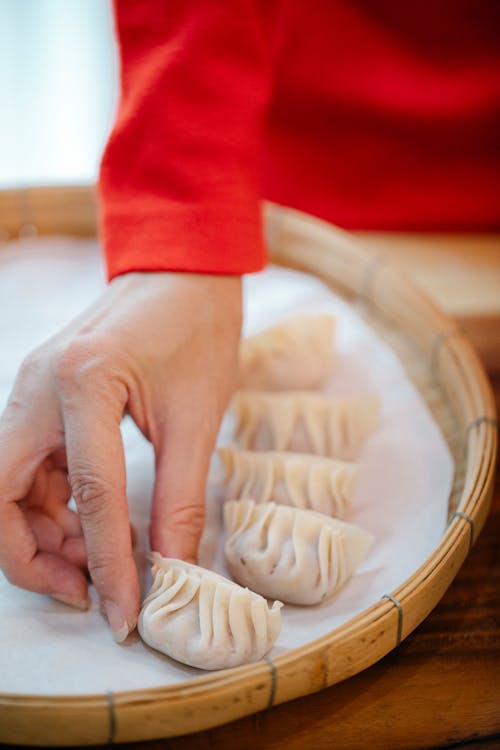 Free Woman placing dumplings on bamboo dish Stock Photo