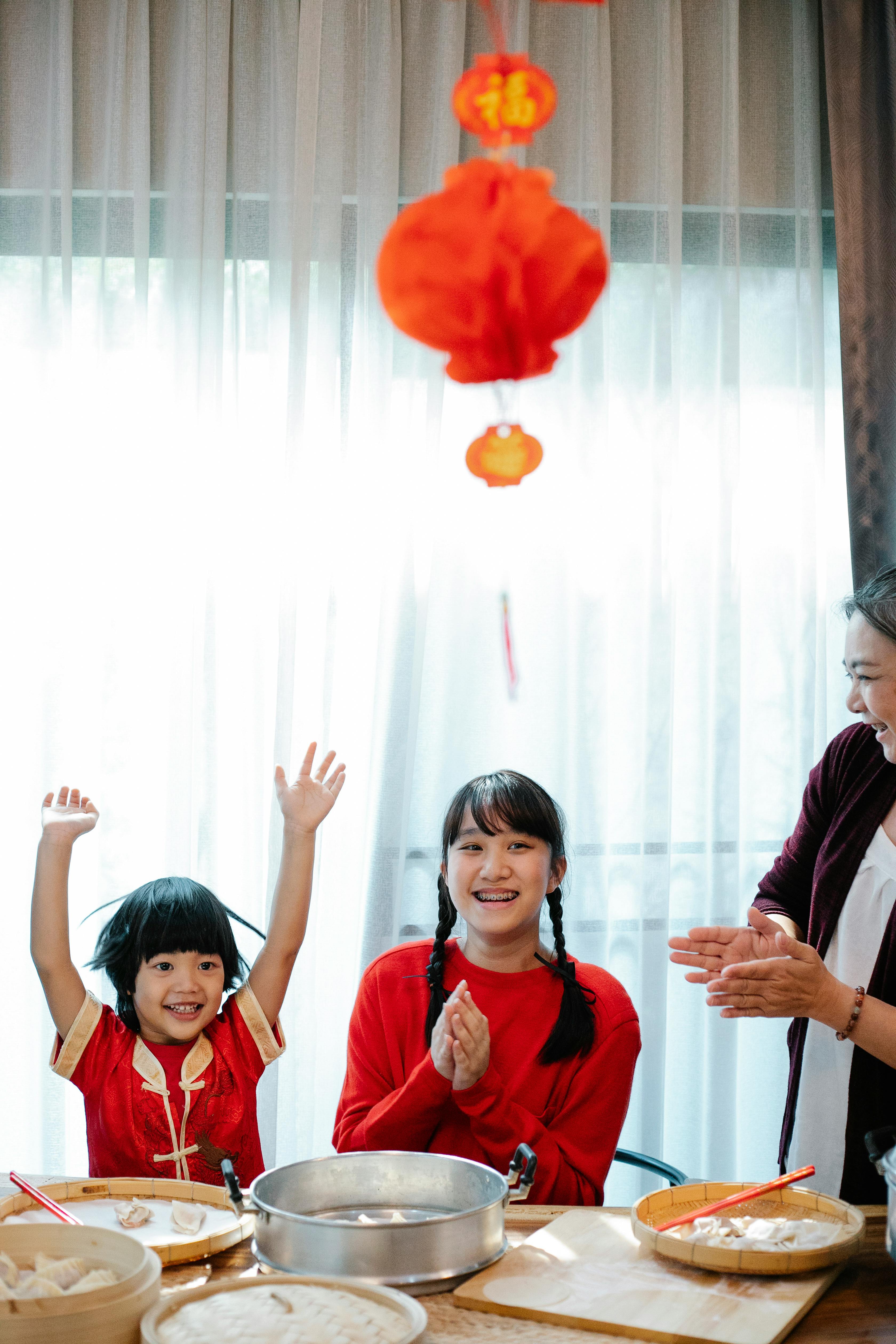 asian siblings and grandmother rejoicing in kitchen