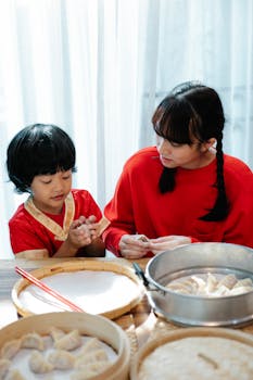 Asian siblings preparing traditional dumplings in a cozy kitchen setting, showcasing family bonding and culinary tradition.