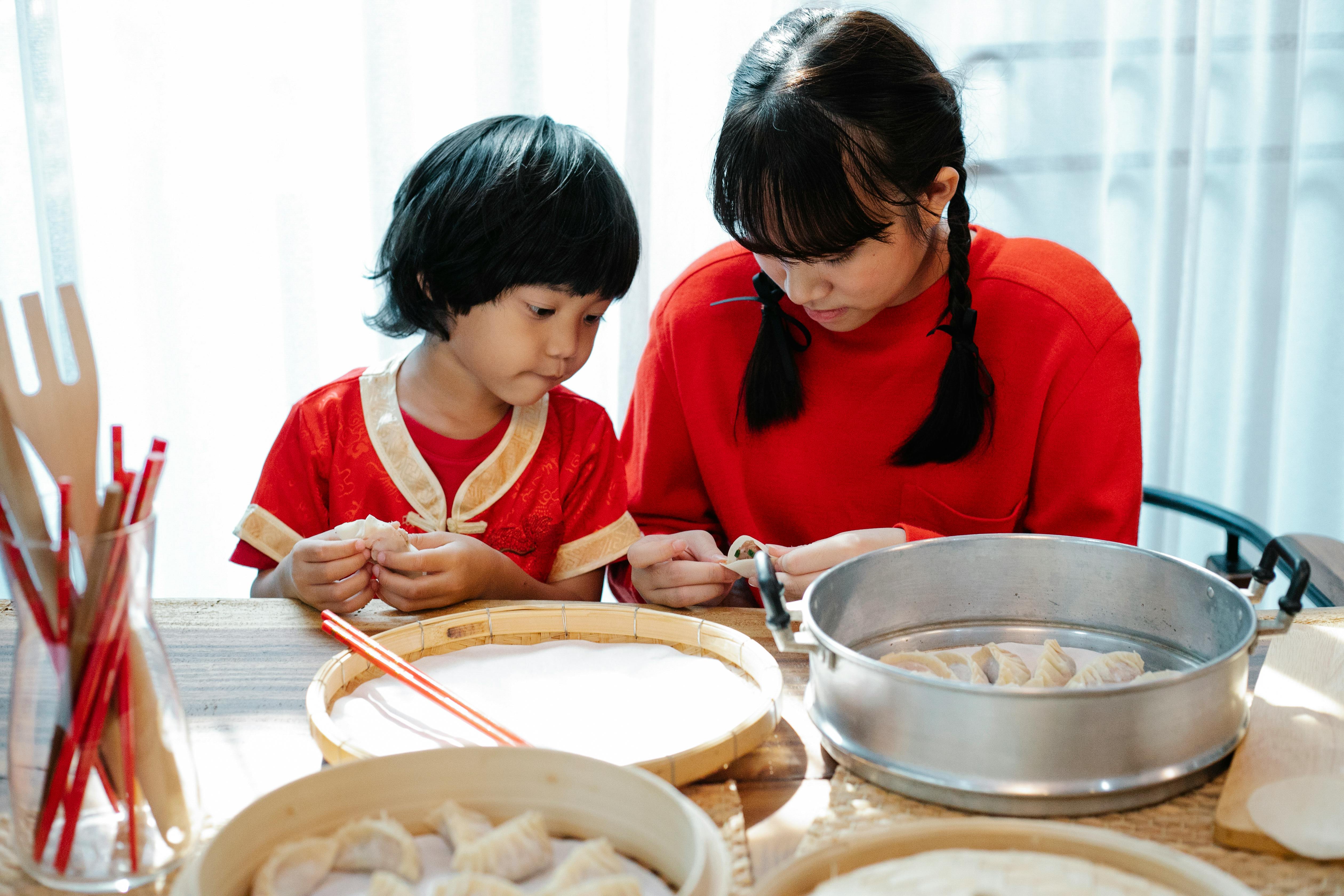 asian teen sister teaching brother to cook dumplings