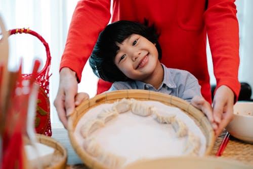 Smiling Asian boy showing handmade dumplings