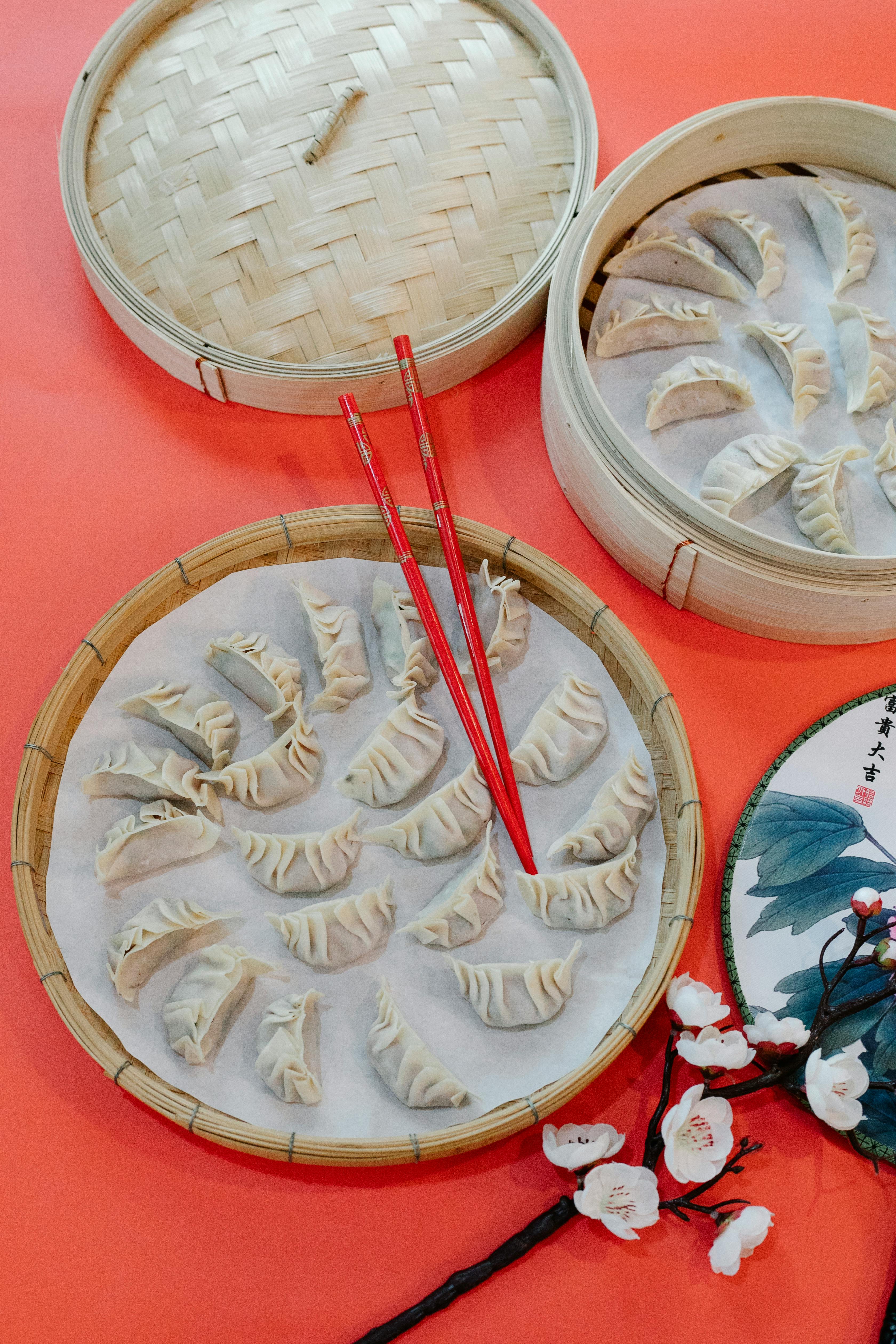 bamboo steamer with raw dumplings and chopsticks