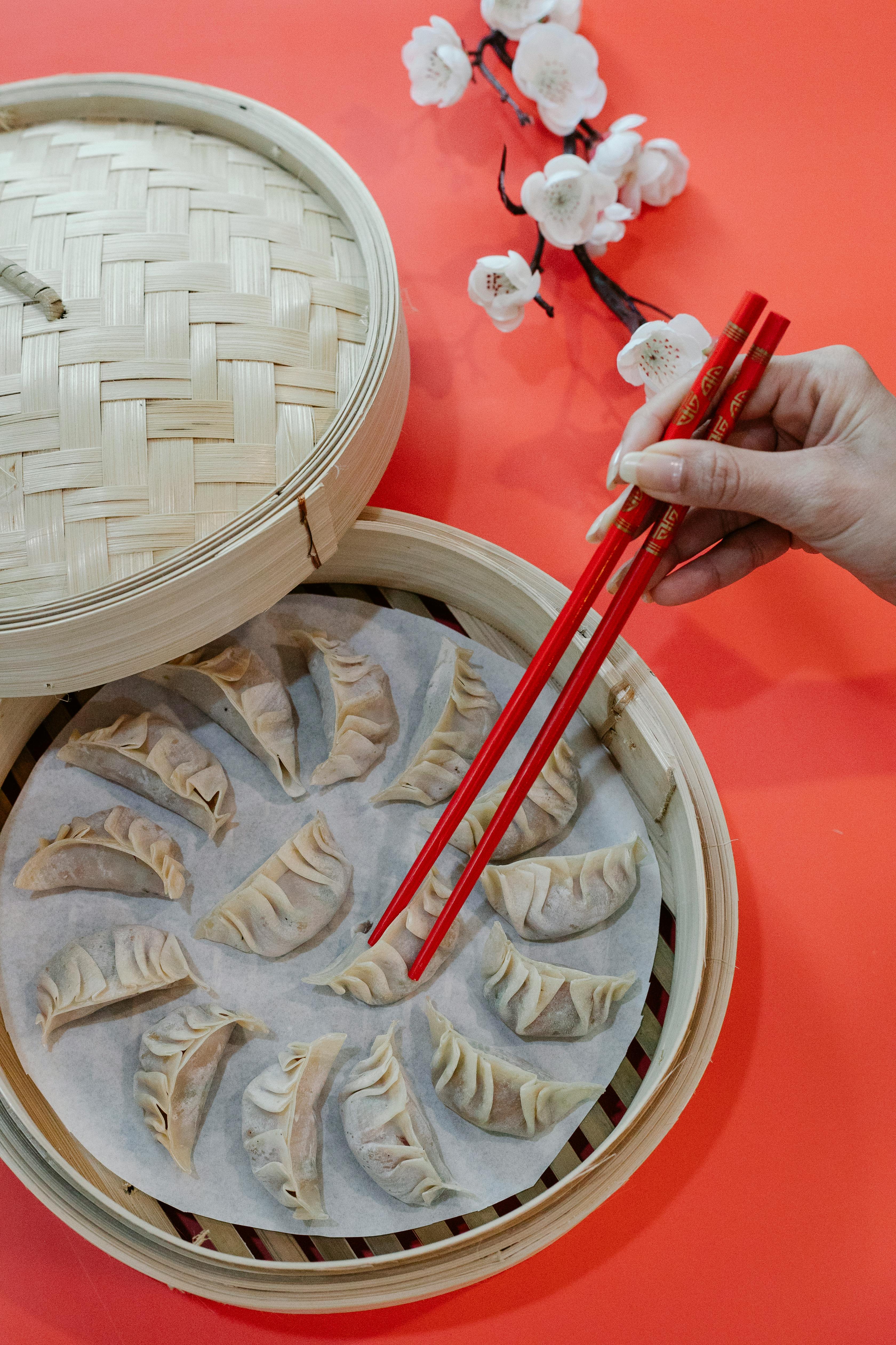 woman putting raw dumpling in bamboo steamer