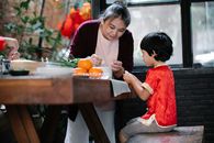 Asian grandmother helping boy to cook traditional food