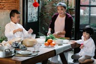 Asian grandmother cooking Chinese food with grandsons