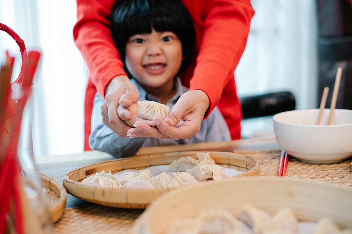 Crazy ethnic boy cooking with mother in kitchen