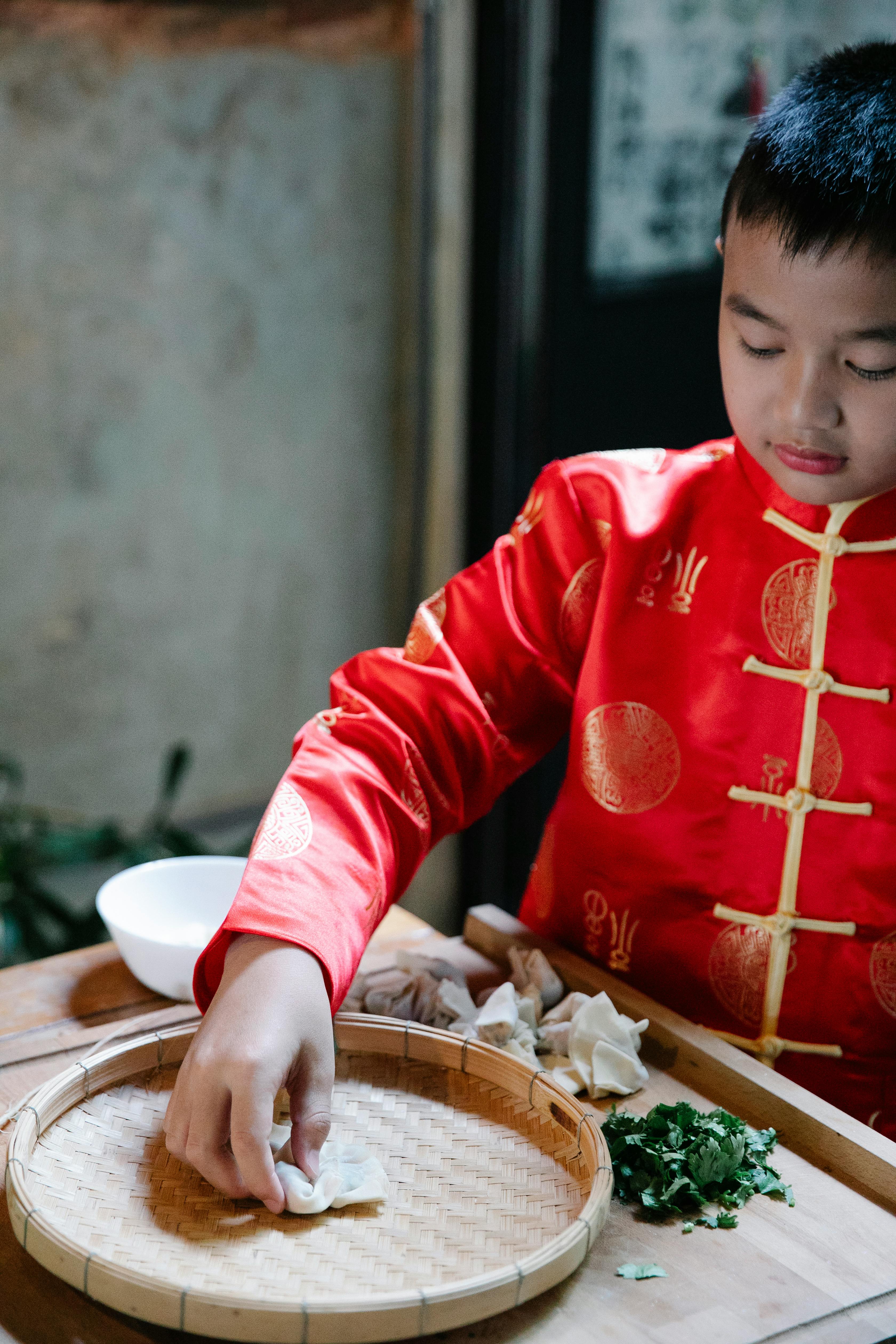 a boy in red clothes making dumplings