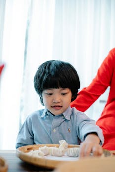Young boy learning to make dumplings with family in a bright home kitchen.