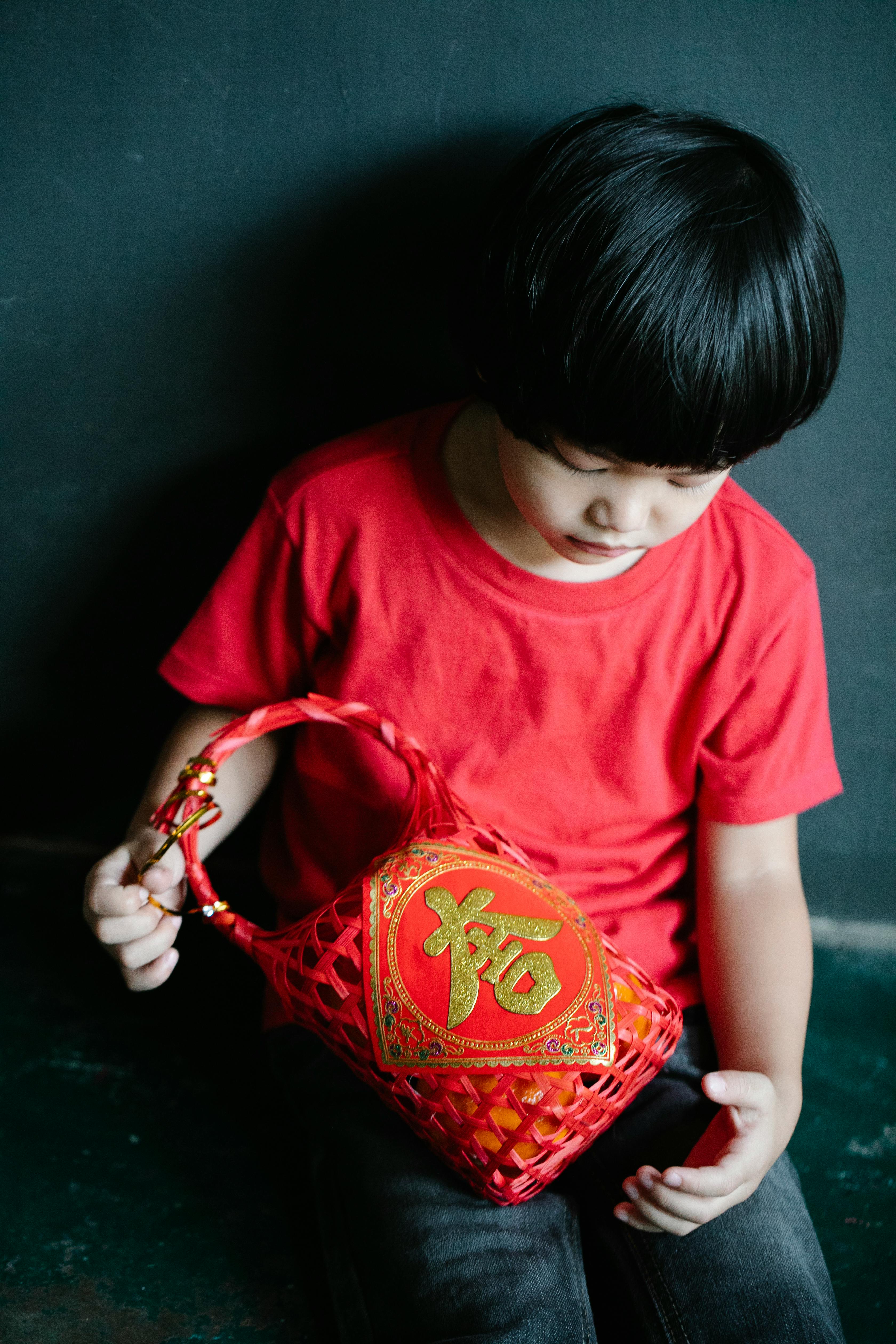 Young child in red shirt holding festive basket for Lunar New Year celebration.