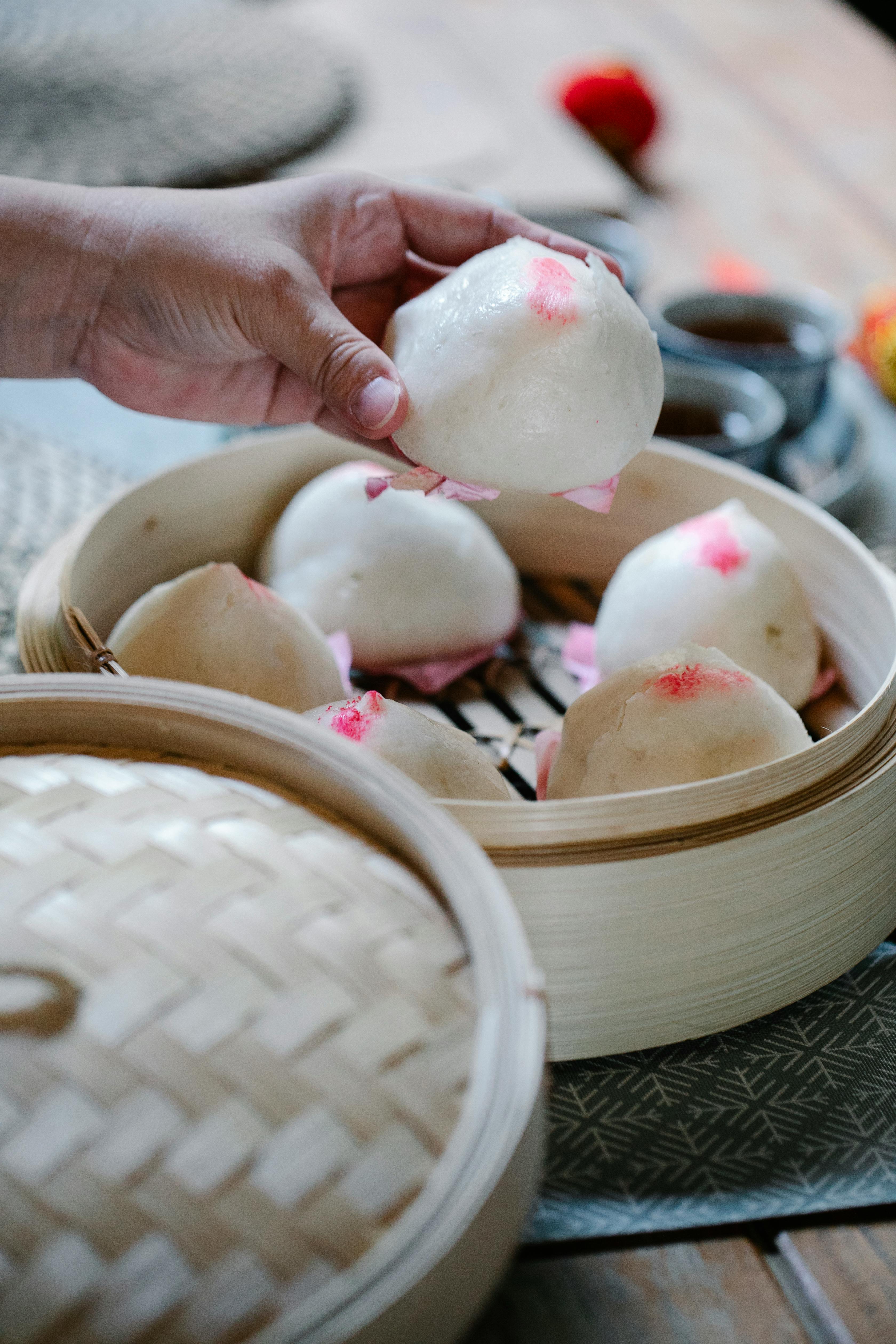 woman taking baozi from bamboo steamer