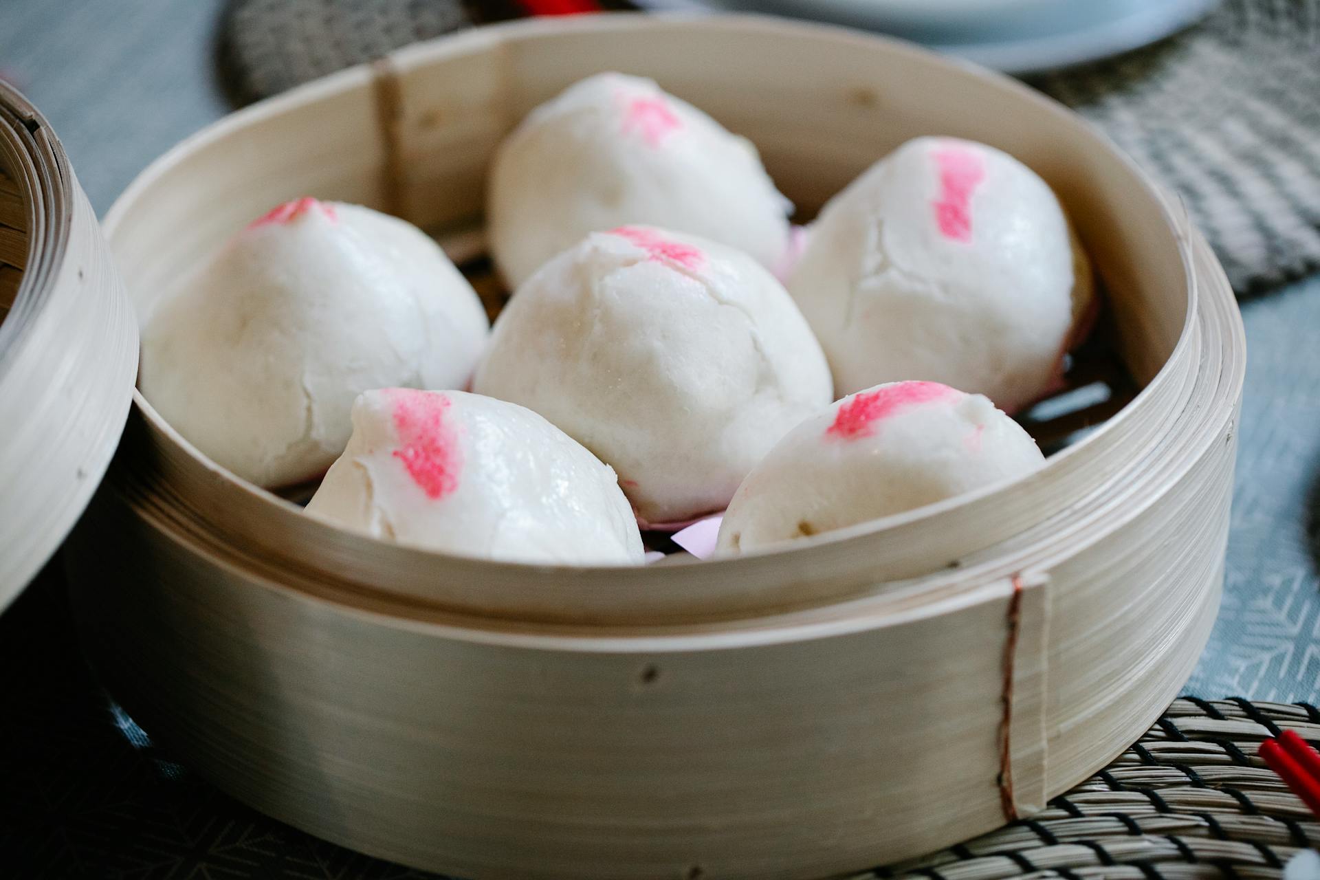 From above of raw Chinese homemade bao in bamboo steamer prepared for traditional lunch