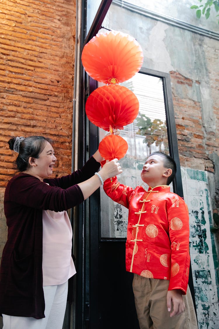 Happy Asian Woman Decorating Doorway With Chinese Lanterns