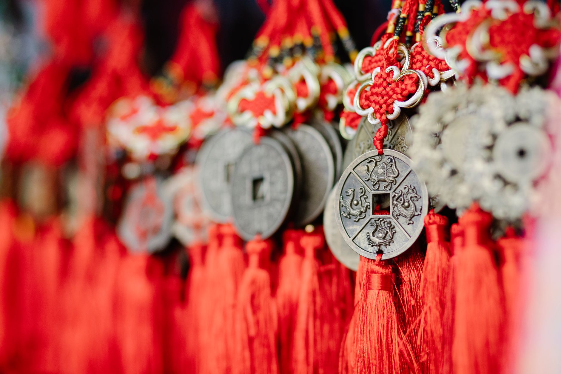 Collection of assorted round amulets in shape of Chinese coins with red satin threads