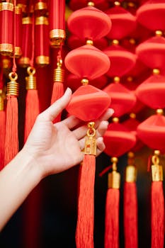 A hand holding red decorative lanterns, symbolizing celebration and tradition.