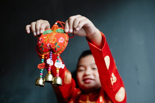 A Boy in Red Clothes Holding a Trinket