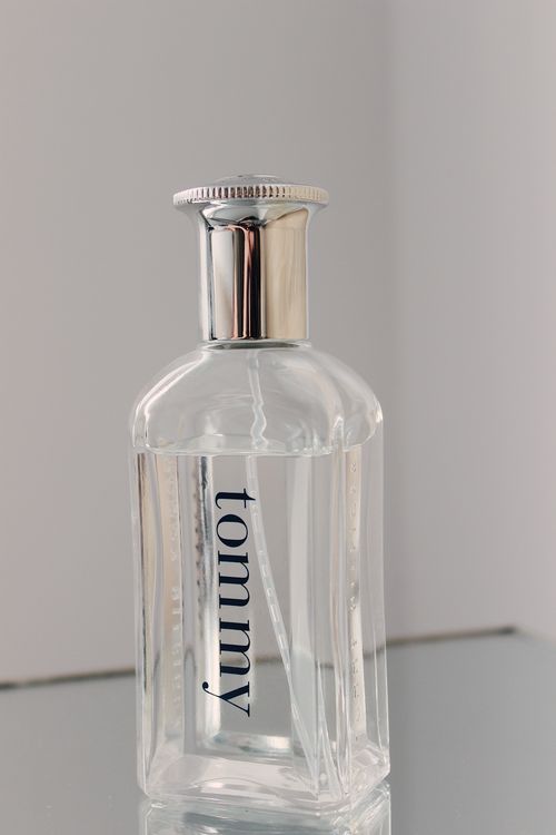 Free Minimalist clear perfume bottle with metallic cap on a reflective surface. Stock Photo
