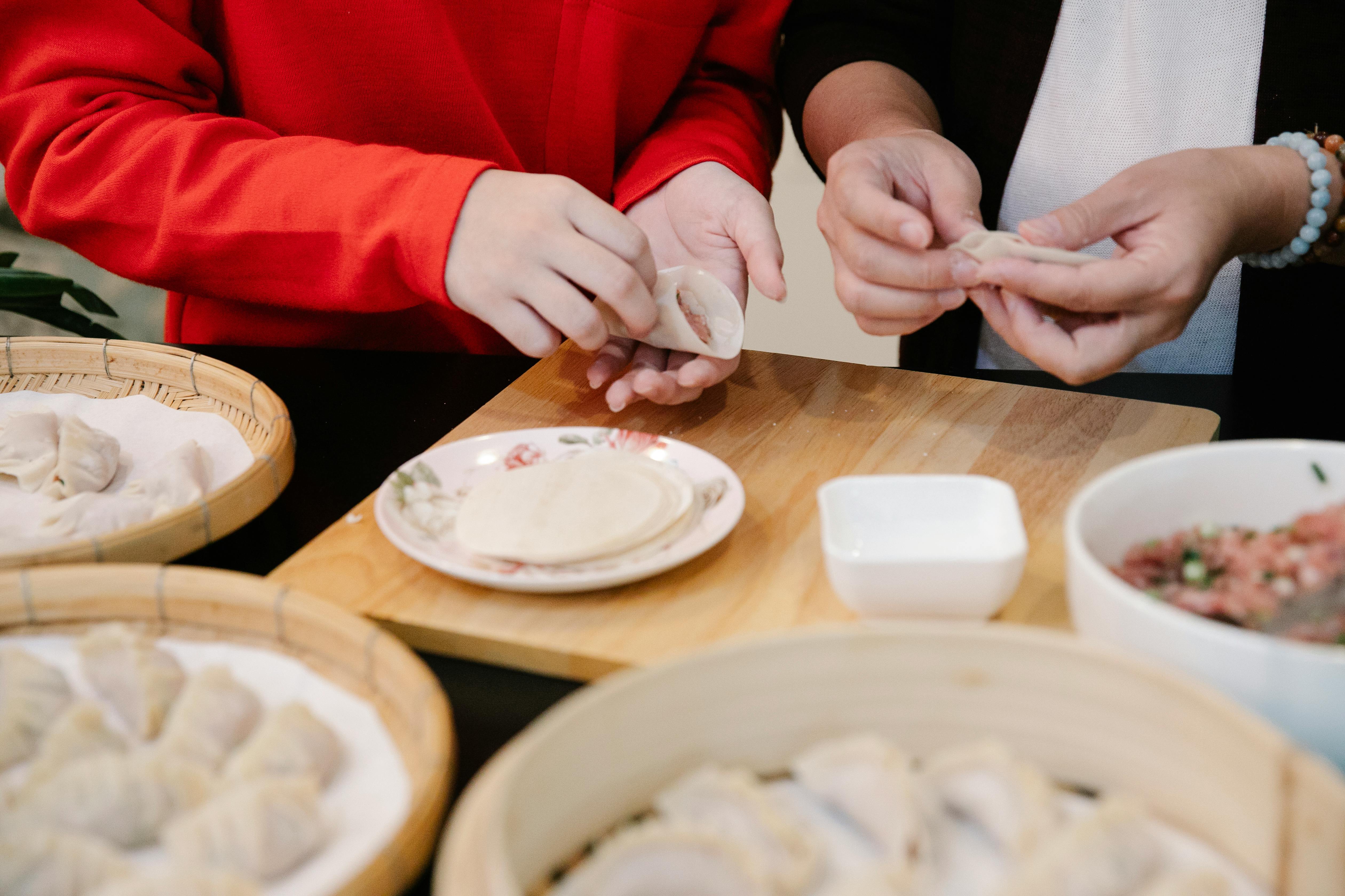 woman making dumplings with daughter in kitchen