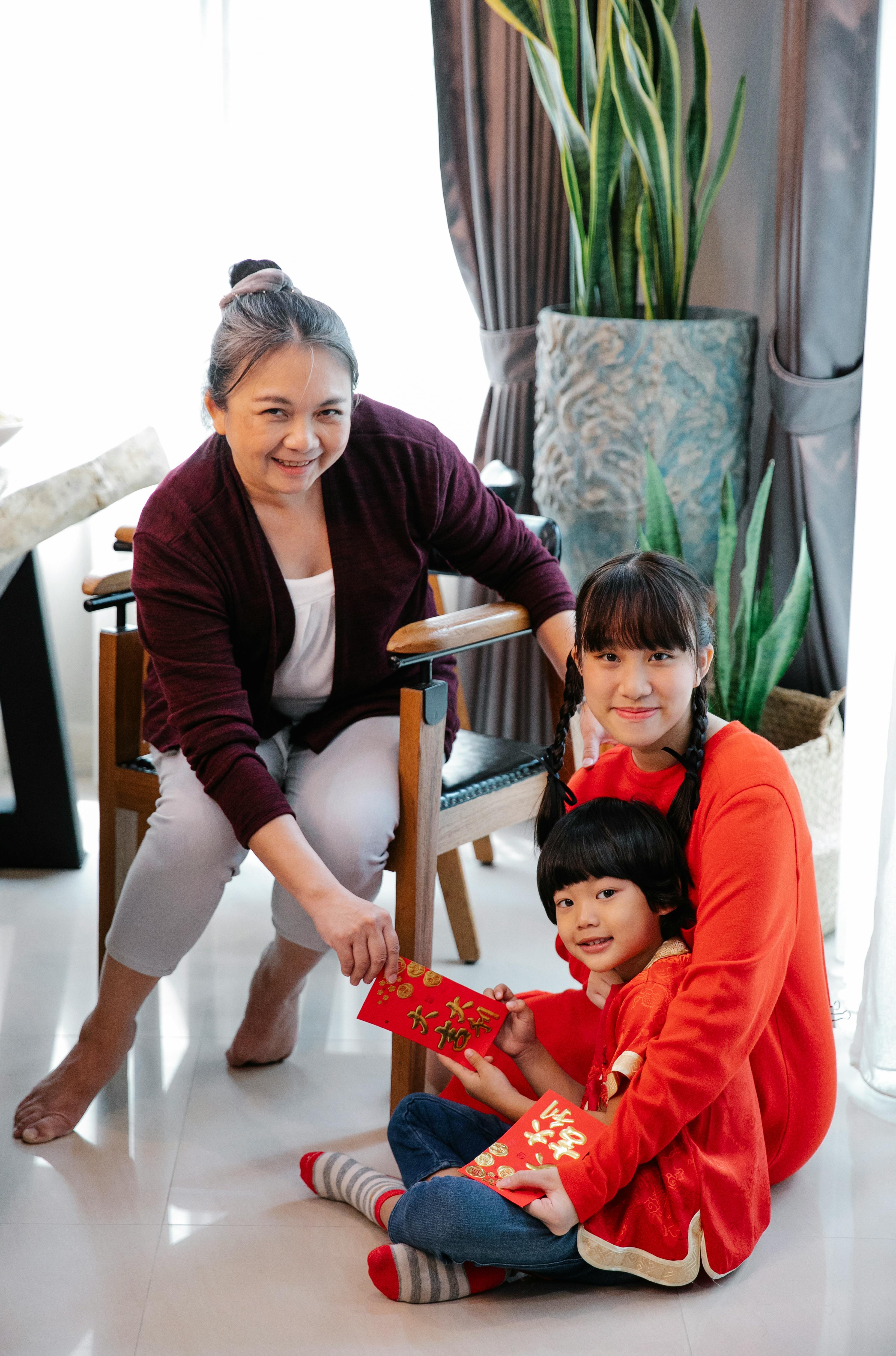 asian grandmother giving envelop to grandson sitting with sister