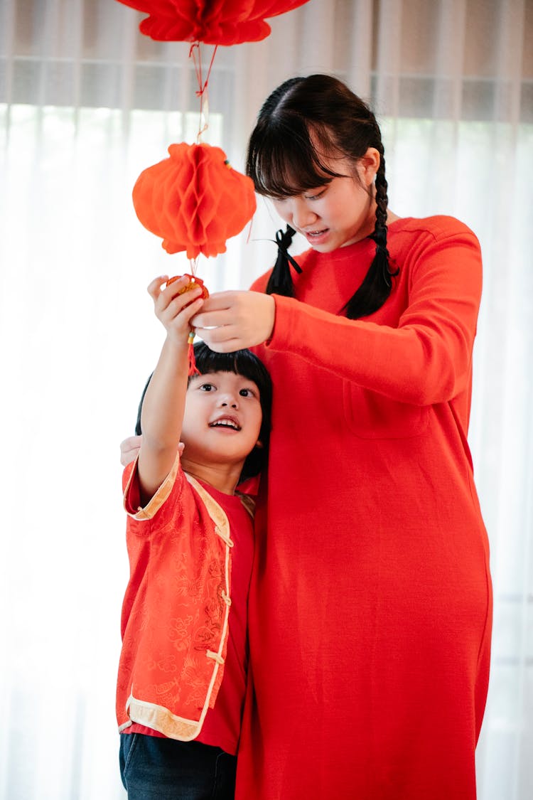 Asian Teen With Brother Decorating Home With New Year Lantern