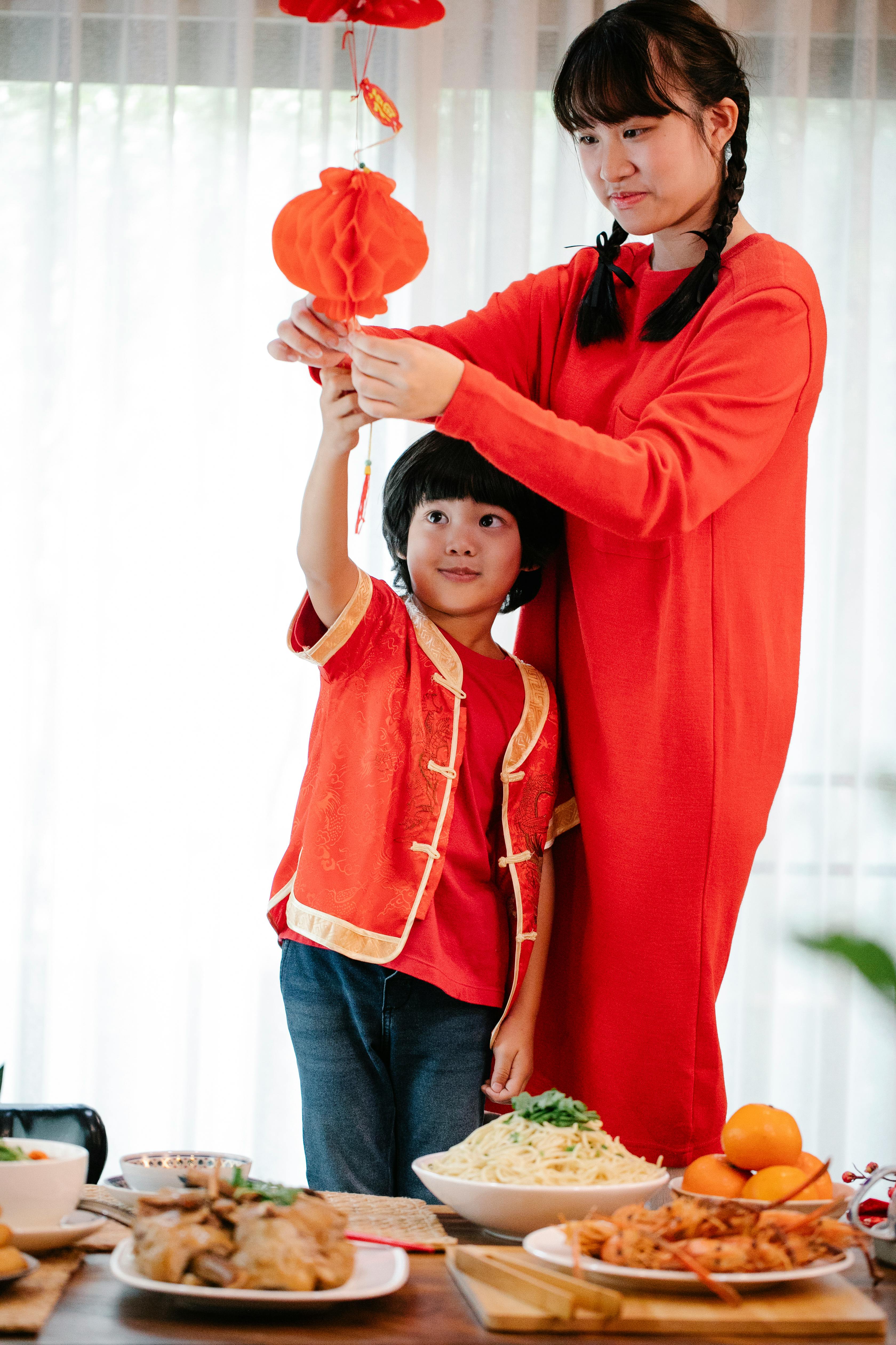 asian teen with brother decorating home with red lantern