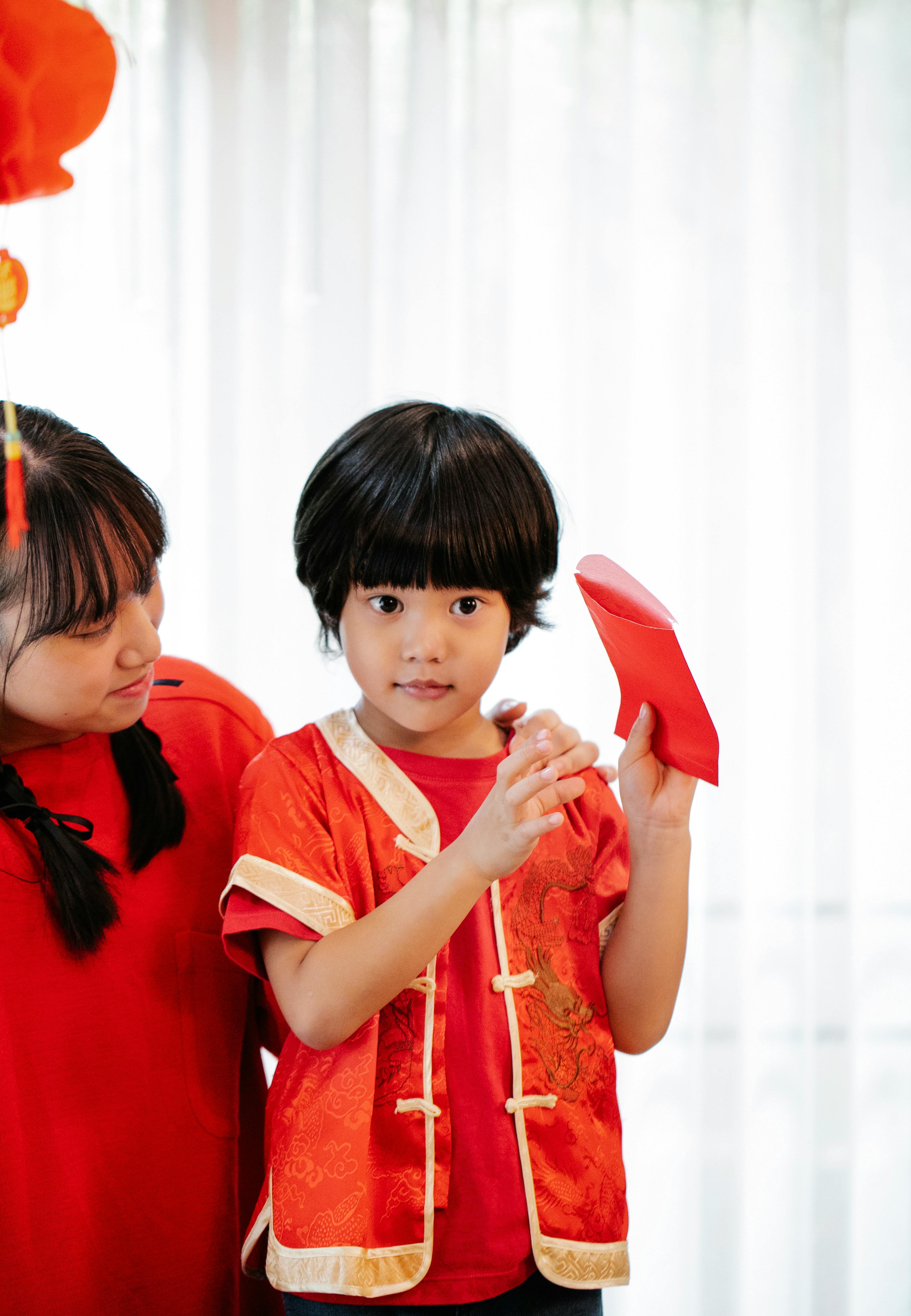 asian boy with red packet against crop sister at home