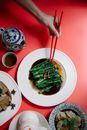 Crop woman with chopsticks above bok choy in soy sauce