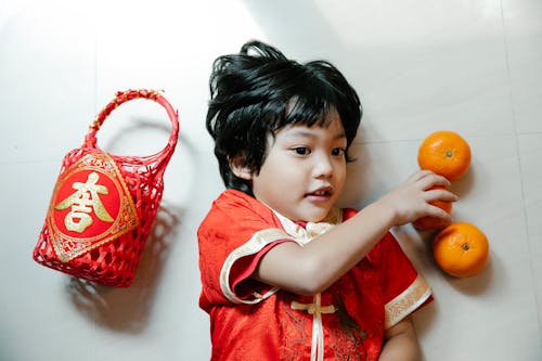 A Child in Red Clothing Lying Down on the Floor