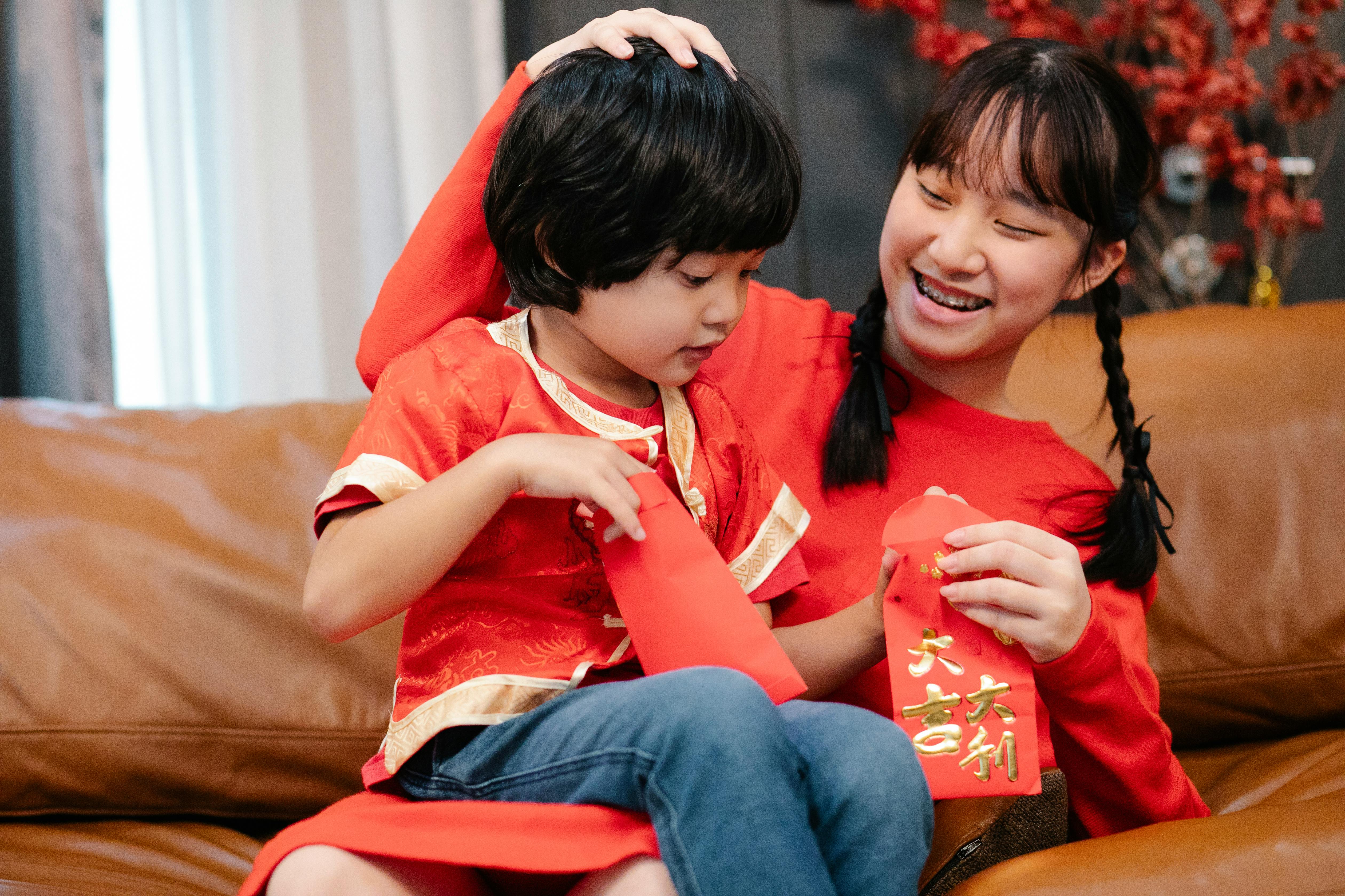 siblings spending time together while holding red envelopes